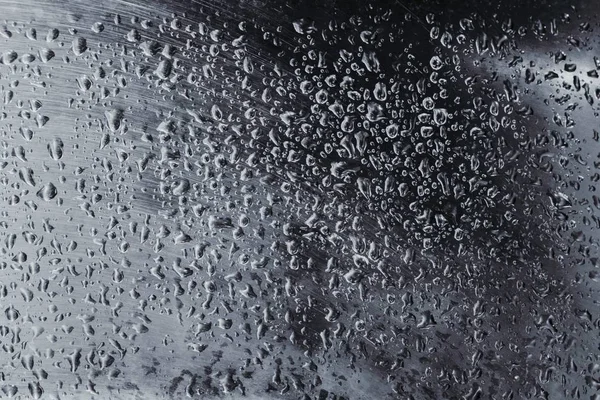 Abstract background with water drops on a silver metal sheet.