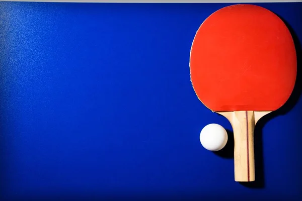 テーブルテニスのための赤ラケットとボールを青のテーブルの背景に — ストック写真
