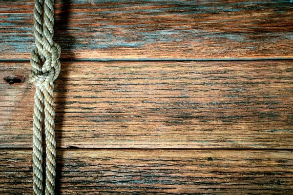 Ship rope knot on old wooden texture background