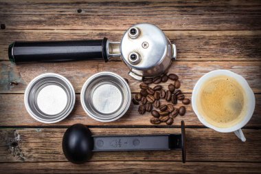 Kahve makinesi aksesuarlı kahve fincanı ve ahşap bir masada fasulye.