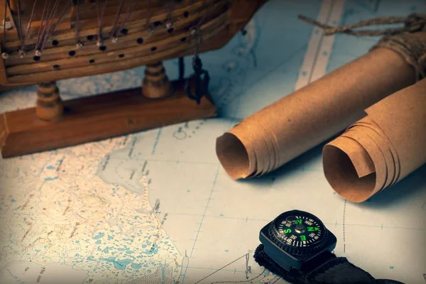 Background with a scroll of old paper, a magnetic compass, a sailboat and a geographical map.