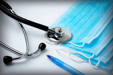  Beyaz arka planda steteskop, kalem ve tıbbi koruyucu maskeler