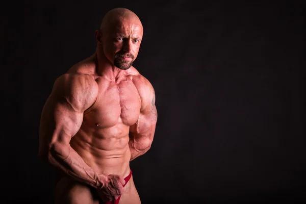 Masculino mostrando músculos no escuro fundo . — Fotografia de Stock