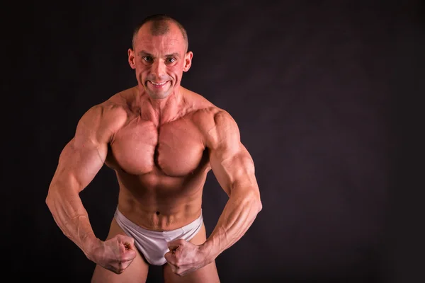 Emotional bodybuilder on black — Stock Photo, Image