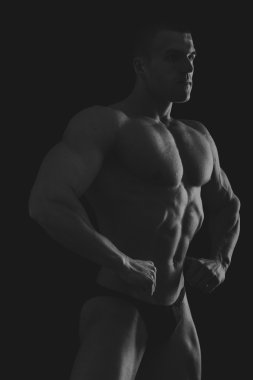 Karanlık bir arka plan üzerinde vücut geliştirmeci silüeti.