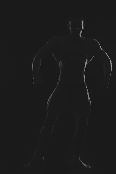 Silhouette eines Bodybuilders auf dunklem Hintergrund. — Stockfoto