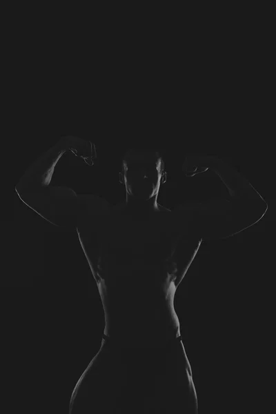 Silhouette eines Bodybuilders auf dunklem Hintergrund. — Stockfoto