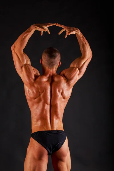 Uomo muscoloso con manubri su nero — Foto Stock