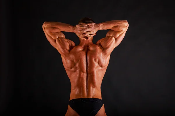 Homem muscular com halteres em preto — Fotografia de Stock