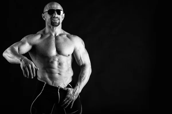 Muscular, relief body bodybuilder on a black background. Black a — Stock Photo, Image