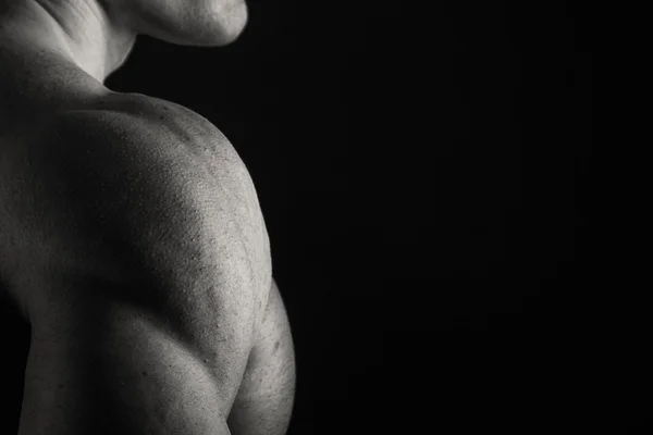 Muscoloso, bodybuilder sollievo su uno sfondo nero. Nero a — Foto Stock