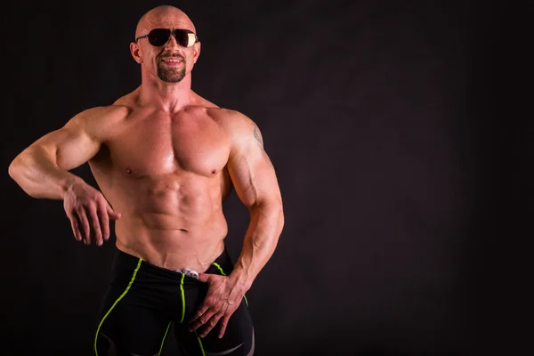 Invloed-down bodybuilder bril op een donkere achtergrond. — Stockfoto