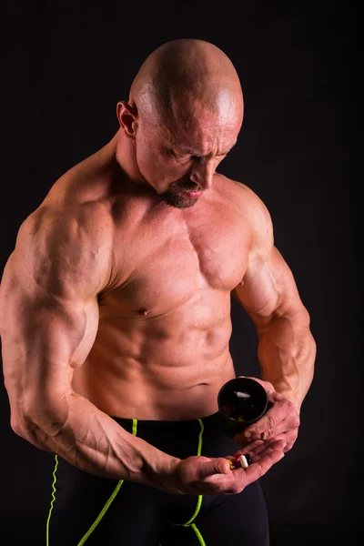 Kraftfull bodybuilder på en mörk bakgrund. — Stockfoto