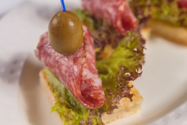 Canapé con salami en un plato blanco . — Foto de Stock