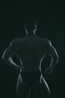 Karanlık bir arka plan üzerinde vücut geliştirmeci silüeti.