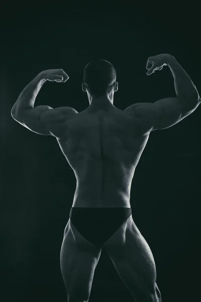 Silhouet van bodybuilder op een donkere achtergrond. — Stockfoto