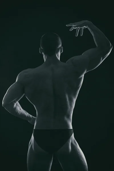 Silhouette eines Bodybuilders auf dunklem Hintergrund. — Stockfoto