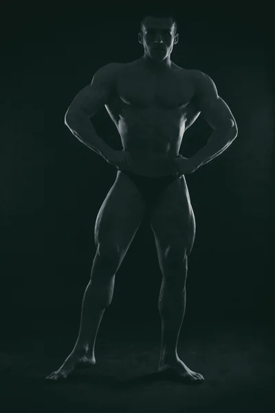 Silhouette eines Bodybuilders auf dunklem Hintergrund. — Stockfoto