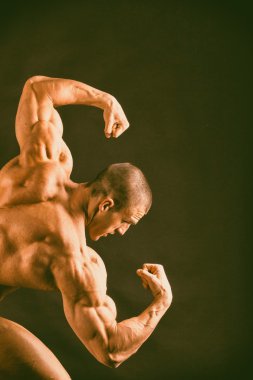 karanlık bir arka plan üzerinde poz vücut geliştirmeci.