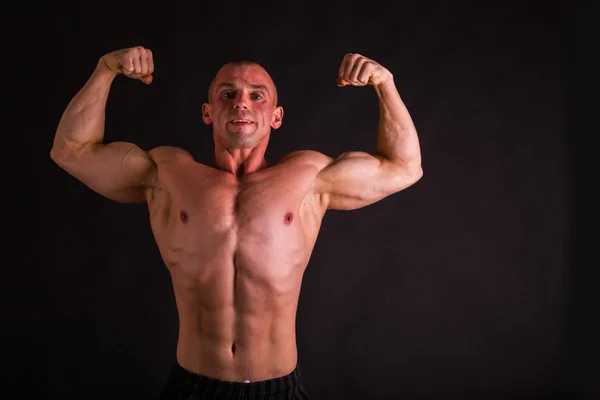 Novizio bodybuilder posa su uno sfondo scuro . — Foto Stock