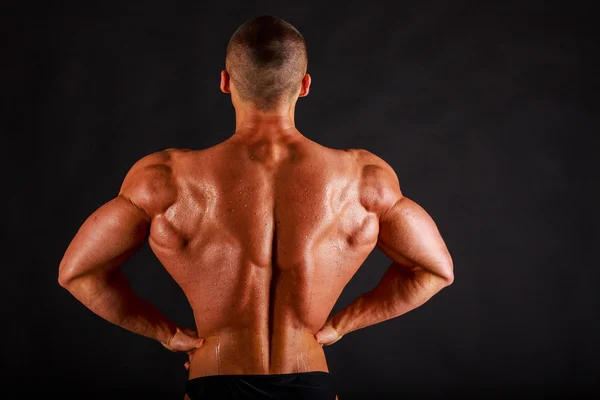 Bodybuilder op een donkere achtergrond. — Stockfoto