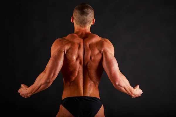 Bodybuilder op een donkere achtergrond. — Stockfoto