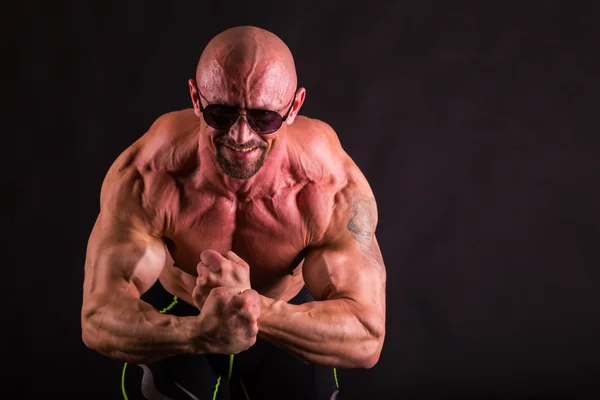 Kraftfull bodybuilder på en mörk bakgrund. — Stockfoto