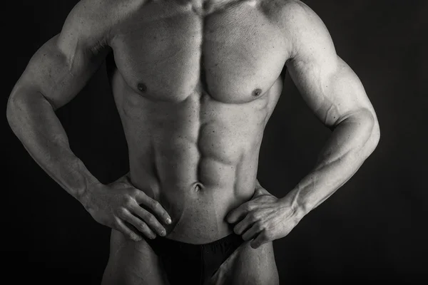 Sterke bodybuilder op een donkere achtergrond. — Stockfoto