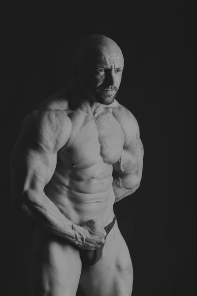 Karanlık bir arka plan üzerinde erkek vücut geliştirmeci. — Stok fotoğraf