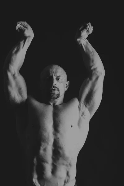 Mannelijke bodybuilder op een donkere achtergrond. — Stockfoto
