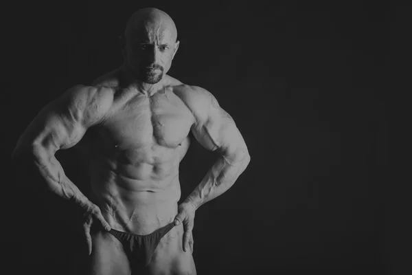Male bodybuilder on a dark background. — Stock Photo, Image