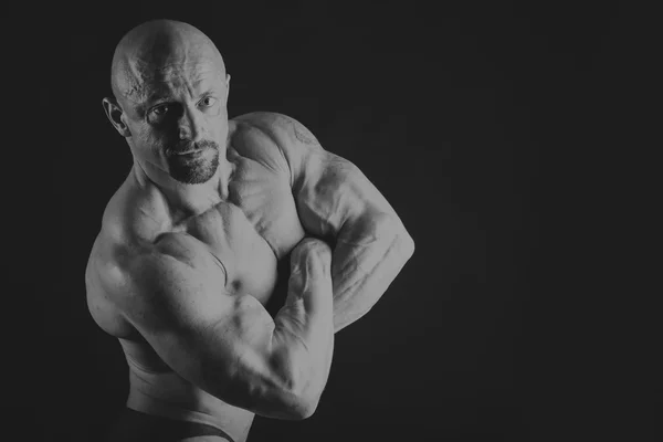 Male bodybuilder on a dark background. — Stock Photo, Image