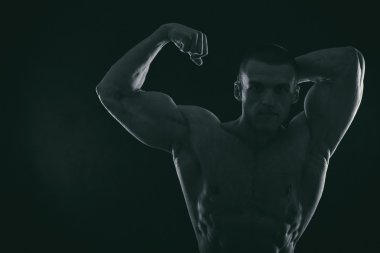 Karanlık bir arka plan üzerinde vücut geliştirmeci silüeti.