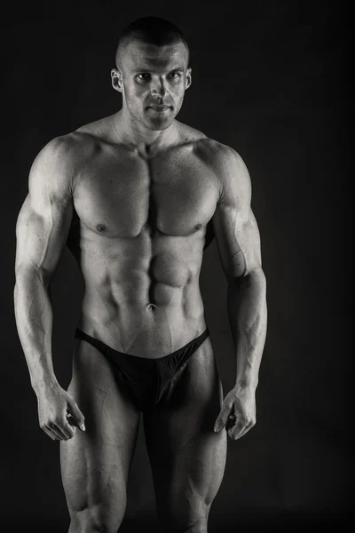 Strong bodybuilder on a dark background. — Stock Photo, Image