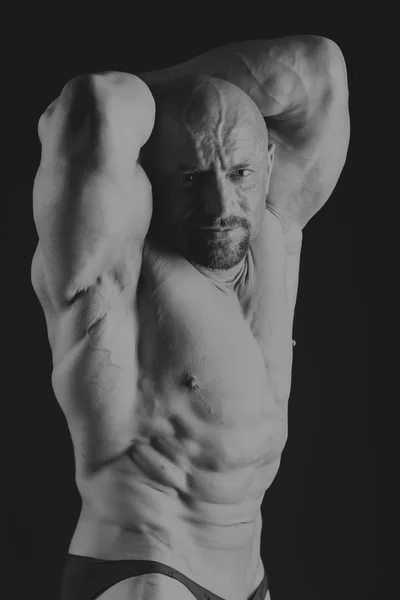 Bodybuilder masculin sur un fond sombre . — Photo