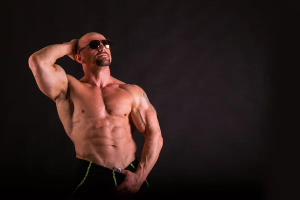 Kraftvoller Bodybuilder auf dunklem Hintergrund. — Stockfoto