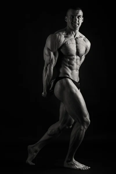 Hombre musculoso sobre un fondo oscuro . — Foto de Stock
