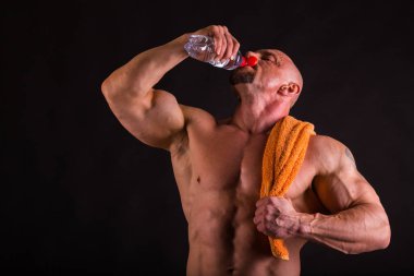 Bir adam siyah bir zemin üzerine muhteşem bir kas vücut ile