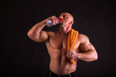 Bir adam siyah bir zemin üzerine muhteşem bir kas vücut ile