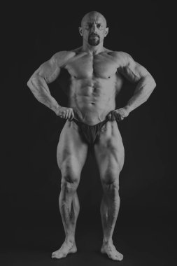 Bir adam siyah bir zemin üzerine muhteşem bir kas vücut ile