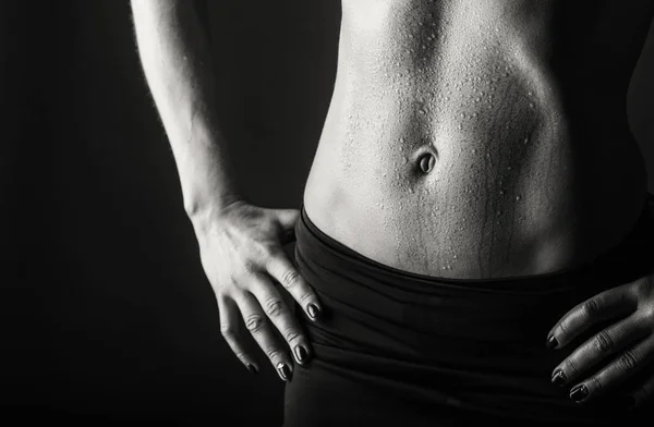 Entrenamiento elegante, mujer musculosa sobre un fondo negro —  Fotos de Stock