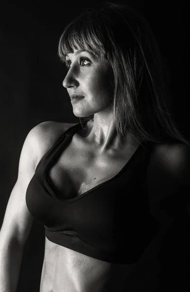 Entrenamiento elegante, mujer musculosa sobre un fondo negro —  Fotos de Stock