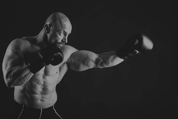 Un hombre con un cuerpo musculoso magnífico sobre un fondo negro — Foto de Stock