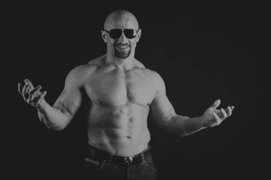 Siyah arka planda poz veren genç kaslı vücut geliştirici.