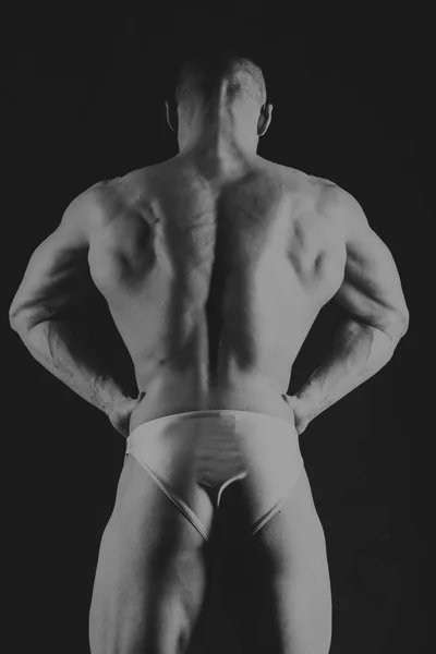 Young muscular bodybuilder posing over black background — Stock Photo, Image