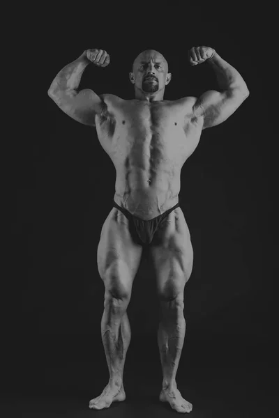 Young muscular bodybuilder posing over black background — Stock Photo, Image