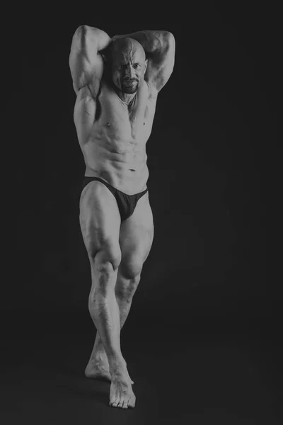 Νέος μυώδης bodybuilder θέτει πάνω από μαύρο φόντο — Φωτογραφία Αρχείου