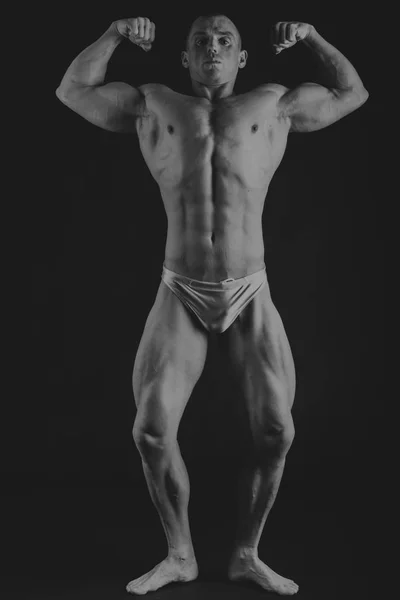 Jeune bodybuilder musculaire posant sur fond noir — Photo