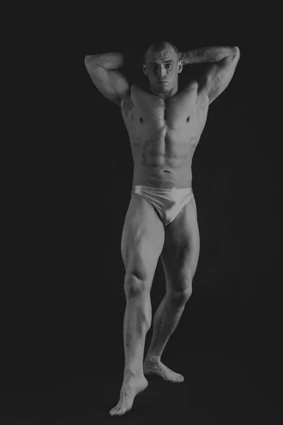Giovane bodybuilder muscolare posa su sfondo nero — Foto Stock