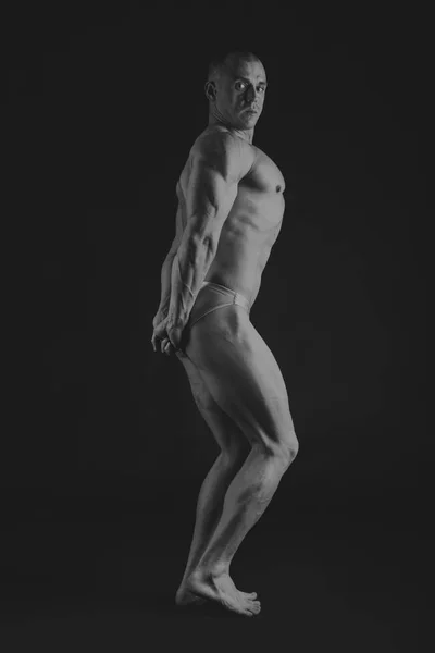Ung muskulös kroppsbyggare poserar över svart bakgrund — Stockfoto